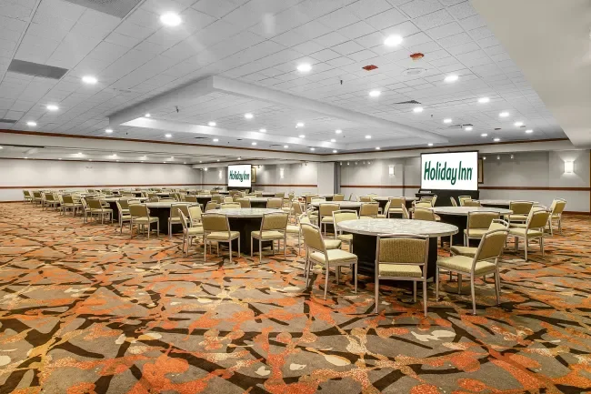 Our ballroom set up with banquet tables, a stage and two projections screens